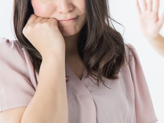 悩む女性と背後から制止を促す手