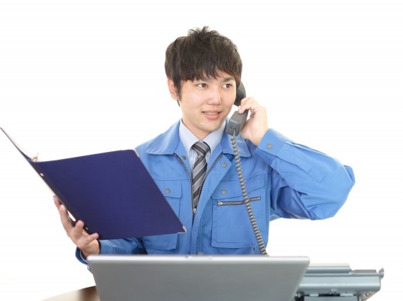 バインダーを手に電話対応する男性作業員
