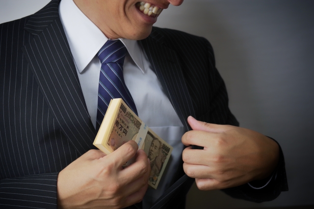 懐に大金を入れ笑みを浮かべるスーツ男性