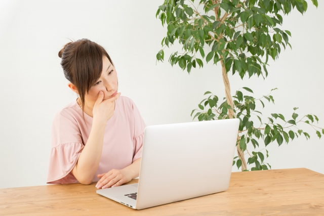 パソコンの前で悩む女性"