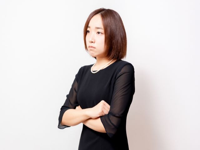 喪服を着て腕を組む女性