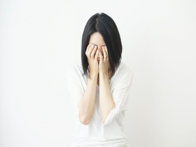 両手で顔を覆う女性